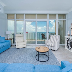 Spacious living area, where comfortable seating and large windows frame beautiful beachfront views