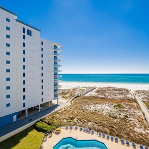 Balcony views showcase the inviting pool area and the tranquil beach, framed by the vibrant blue gulf waters