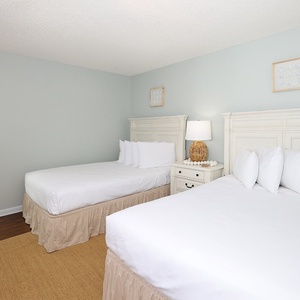Rest in this tranquil guest bedroom featuring two double beds, soft linens, and coastal decor
