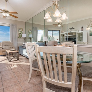 Living area featuring a cozy sofa with queen sofa, dining table, and large windows offering a view of the beach