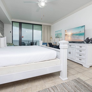 Relax in this spacious master bedroom featuring a comfortable king bed, a large TV, and access to a balcony for fresh air