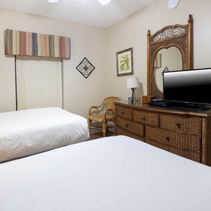 Rest in this guest bedroom featuring two double beds, a TV, and charming decor for a comfortable stay