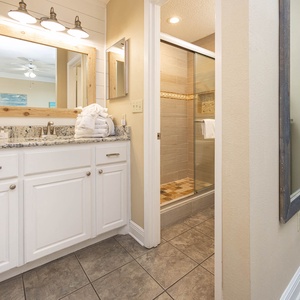 Bright master bathroom featuring a granite countertop, modern fixtures, and a walk-in shower with stylish tile accents