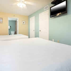 Relax in this guest bedroom featuring two queen beds, a TV, and soft colors that create a welcoming atmosphere