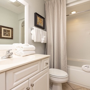 Refresh in the guest bathroom featuring a spacious vanity, neatly stacked towels, and a shower/tub combination for