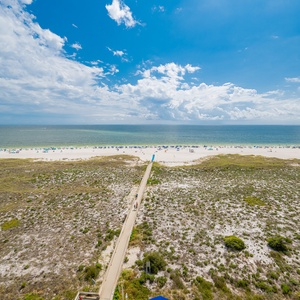 Expansive view of the beach with colorful umbrellas, showcasing the white sand and vibrant Gulf waters under a bright sky