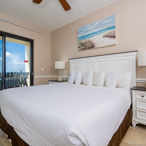 Relax in the master bedroom featuring a king bed, stylish decor, and access to a scenic beachfront balcony