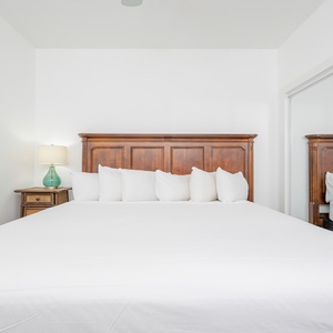 Guest bedroom featuring a large queen bed with plush pillows and a stylish wooden headboard