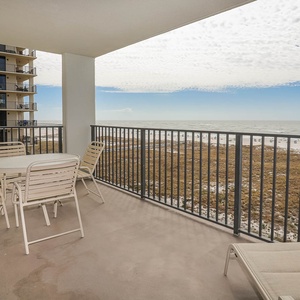 Balcony with a table and chairs offers a view of the beach and gulf, perfect for enjoying the coastal breeze