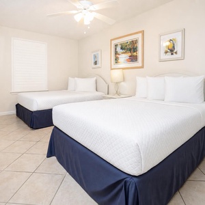 Inviting guest bedroom featuring two double beds, soft lighting, and cheerful artwork