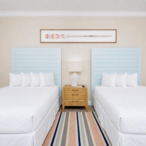 Sleep comfortably in this guest room with two beds, a charming lamp, and a colorful rug