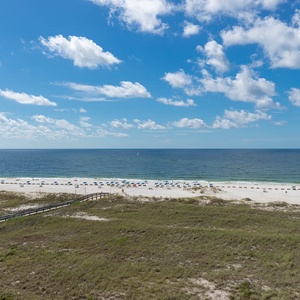 Balcont view of the beach with white sand, colorful umbrellas, and the tranquil gulf under a clear blue sky