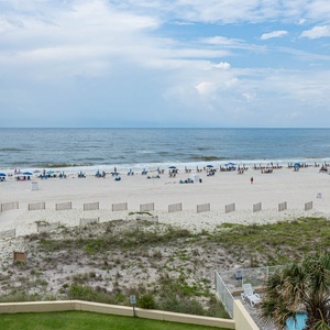 This inviting beach view showcases a serene sandy shore with sunbathers and umbrellas, perfect for relaxation