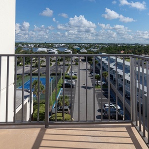 Master balcony view showcases the surrounding area, including tennis courts and lush greenery, inviting relaxation