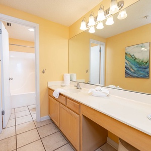 Brighten your morning routine at the spacious vanity with ample counter space, tub-shower, and cheerful yellow walls