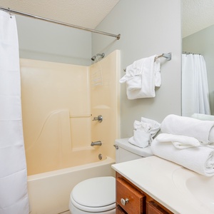 The guest bathroom features a tub/shower combo, neatly arranged towels, and a clean, functional sink area