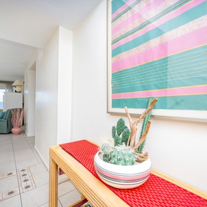 This bright living area features a colorful artwork, cozy seating, and a view of the beachfront through large windows