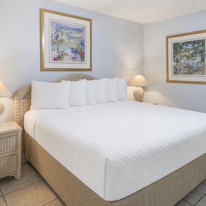 Cozy bedroom featuring a large king bed, soft linens, and tasteful artwork, complemented by warm lighting from bedside lamps