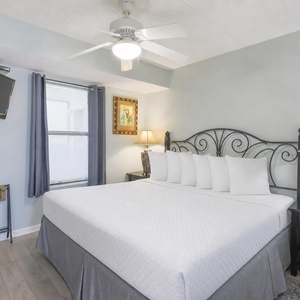 Inviting bedroom featuring a comfortable king bed, a flat-screen TV, and soft natural light from the window