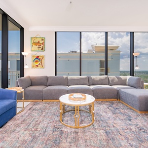 Relax in the spacious living area, featuring a large sectional, vibrant blue chairs, and stunning beachfront views
