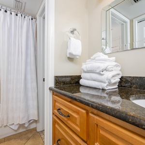 Soft white towels await in the master bath beside the polished granite countertop and shower curtain