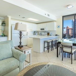 Cozy living space featuring a plush sofa, breakfast bar with seating, and a view of the beach through large windows