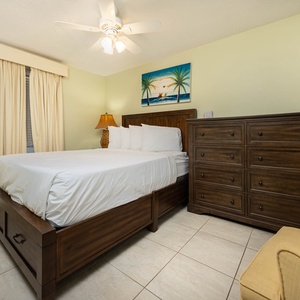 Cozy guest bedroom features a queen bed, a wooden dresser, and a flat-screen TV, complemented by soft green walls