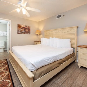 Bright and inviting guest bedroom featuring a king bed, decorative rug, and a cozy reading lamp beside a nightstand