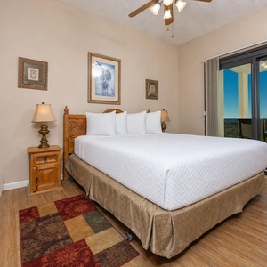 Master suite features a king bed, wooden accents, and sliding doors leading to the extended balcony with a beach view
