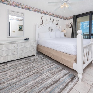 Inviting master suite featuring a king bed, decorative accents, and beachfront balcony access
