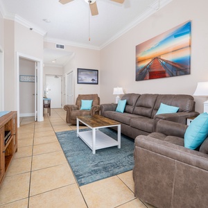 Unwind in the inviting living area with plush seating, a large TV, and decorative coastal art enhancing the ambiance