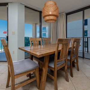 Gather around the rustic wooden dining table, enjoying views and natural light from the beachfront balcony