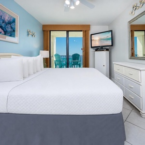 King master suite features crisp linens and a TV for cozy nights after stepping out onto your balcony