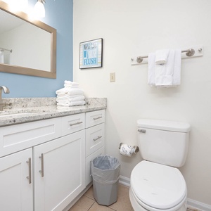 The master bathroom features a granite countertop, bright blue accent wall, and neatly stacked towels for a refreshing stay