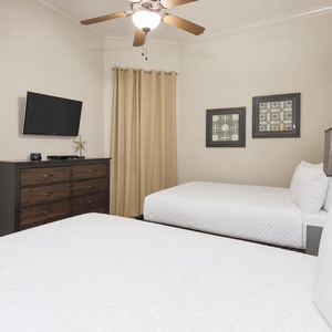 This bedroom features two comfortable queen beds, a mounted TV, and stylish decor for a relaxing stay