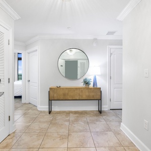 This welcoming entryway features a stylish console table, a round mirror, and a cozy lamp, creating a bright first impression