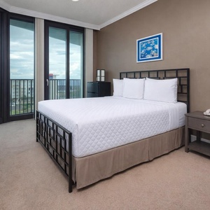 Guest bedroom featuring a cozy queen bed, stylish decor, and expansive windows offering a lovely view