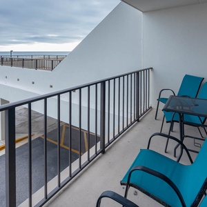 Relax on the private balcony with turquoise chairs, enjoying views of the pristine beach just steps away