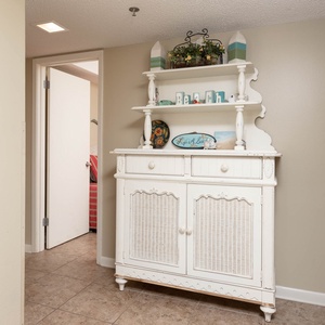 Charming entryway features a white cabinet with decorative accents and beach decor, creating a welcoming atmosphere