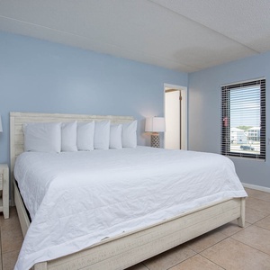This bedroom features a plush king-size bed, stylish nightstands, and a bright window view of the surroundings