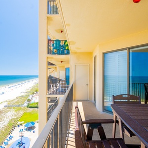 A sweeping view showcases the tranquil beach with soft white sand and colorful umbrellas dotting the shoreline