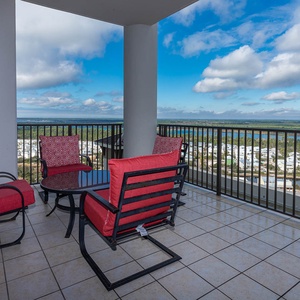 Relax on the balcony with red cushioned chairs and a table, enjoying the serene state park view from the eighteenth floor