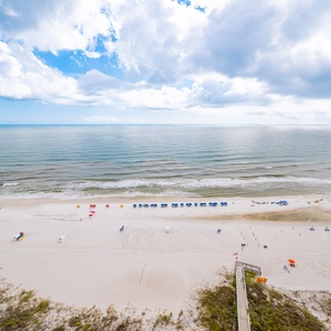 Spectacular view of the pristine beach with colorful umbrellas and chairs under a bright blue sky and fluffy clouds
