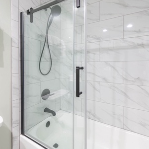 Glass-enclosed shower in the guest bath with a sleek black showerhead and elegant tile, complemented by plush white towels