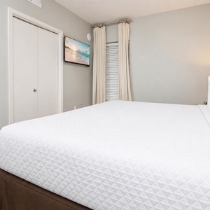 Relax in this comfortable bedroom featuring a king bed, soft lighting, and a TV for your entertainment
