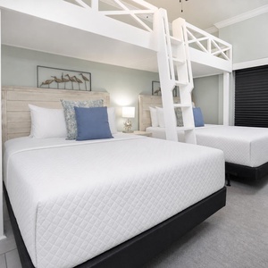 Charming bunk room with two lofted twin beds above two cozy queen beds below