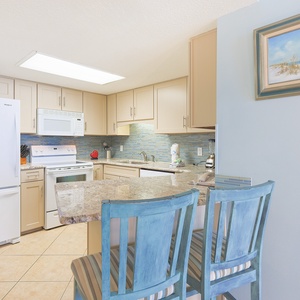 Enjoy meals at the breakfast bar, surrounded by a stylish kitchen featuring white appliances and vibrant decor