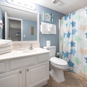 Refreshing guest bathroom featuring a turtle-themed shower curtain, plush towels, and a spacious vanity area