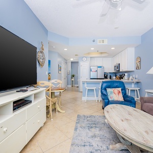 The condo living space features a large TV, cozy seating, and a bright, inviting atmosphere