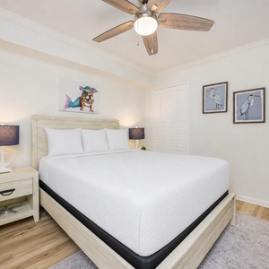 Rest in the guest suite with a queen bed framed by playful coastal art and soft glowing lamps